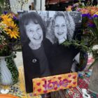 Picture of Carol Grimes and Kelley Grimes with flowers and a sign that says love