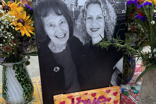 Picture of Carol Grimes and Kelley Grimes with flowers and a sign that says love